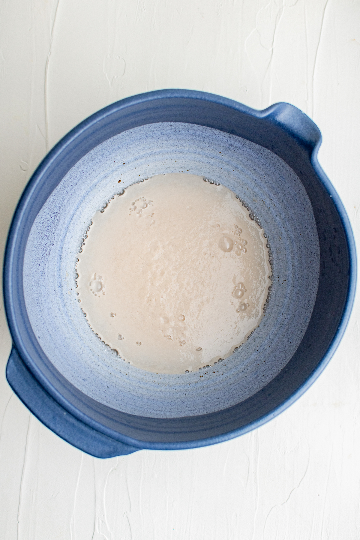 Yeast proofing in a bowl with warm water and sugar.