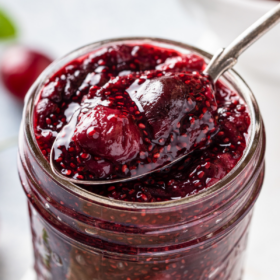 A spoonful of chia cherry jam in a mason jar.