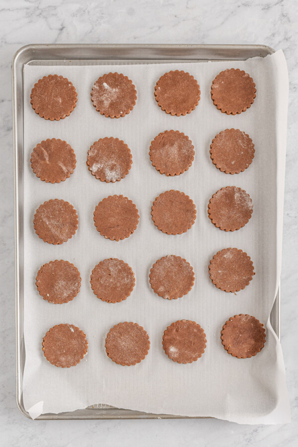Unbaked cookies lined up on a parchment-lined cookie sheet.