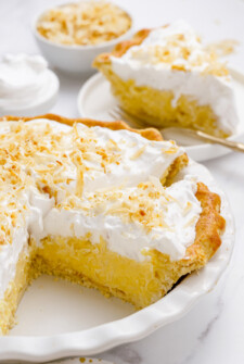 Coconut cream pie in a pie dish with the pie cut into slices.