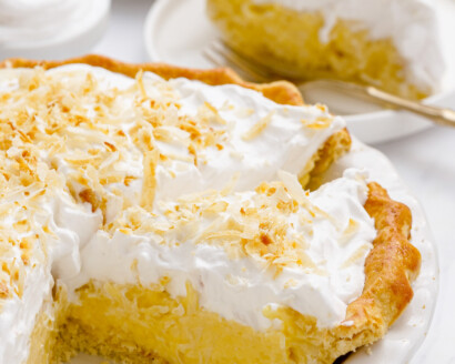 Coconut cream pie in a pie dish with the pie cut into slices.