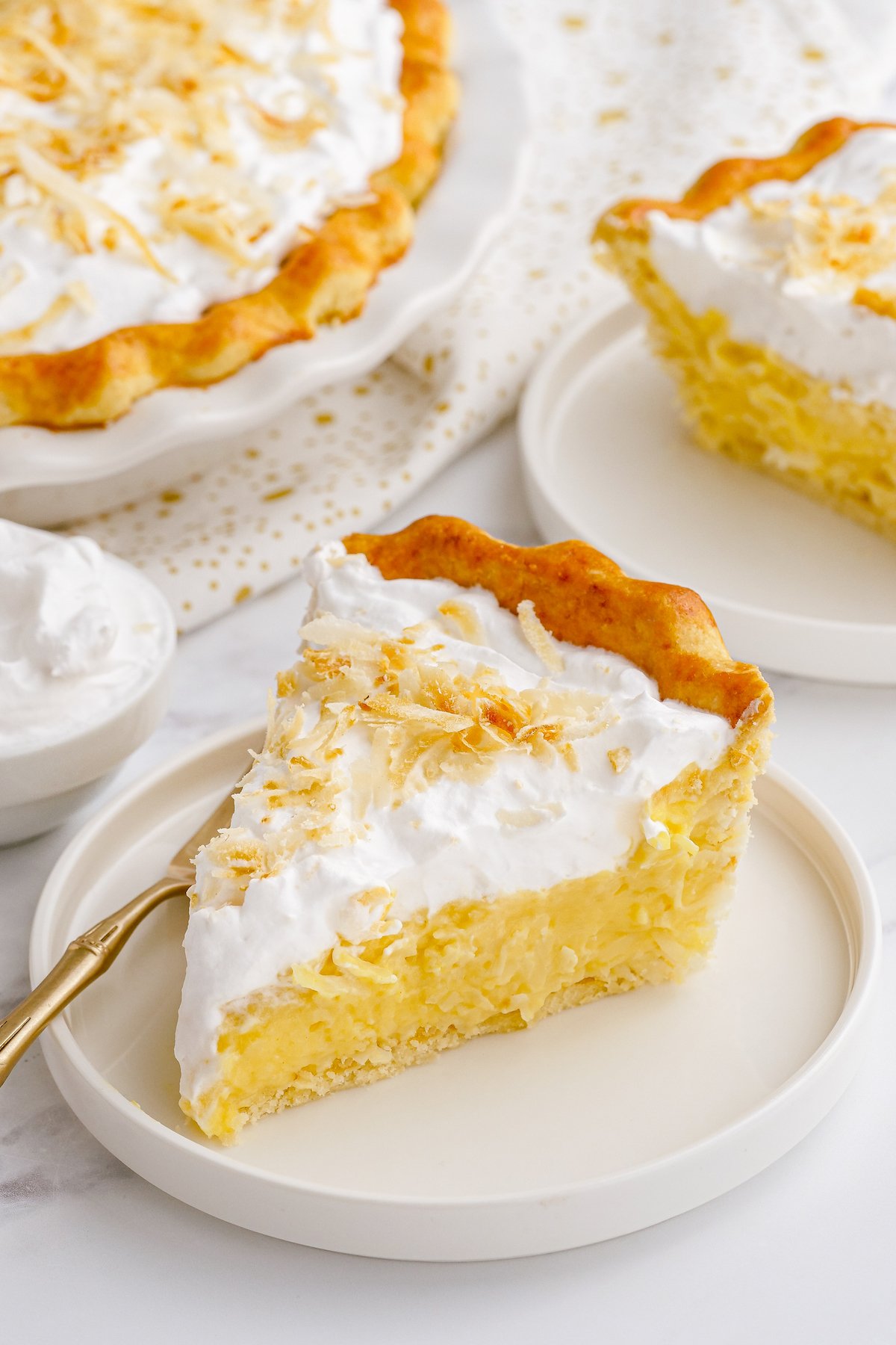 A slice of homemade coconut cream pie on a white plate with a fork.