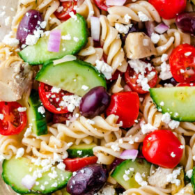 Overhead image of greek pasta salad in a clear glass bowl.