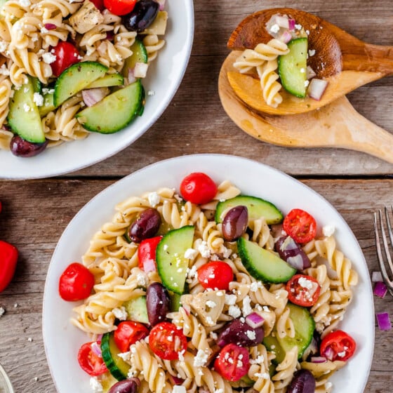 Overhead image of two bowls of pasta salad with two wooden spoons.