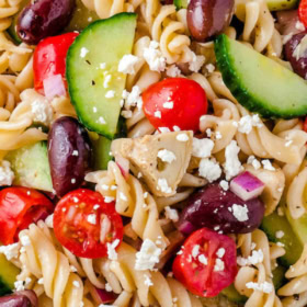 A white plate filled with pasta salad with feta cheese.
