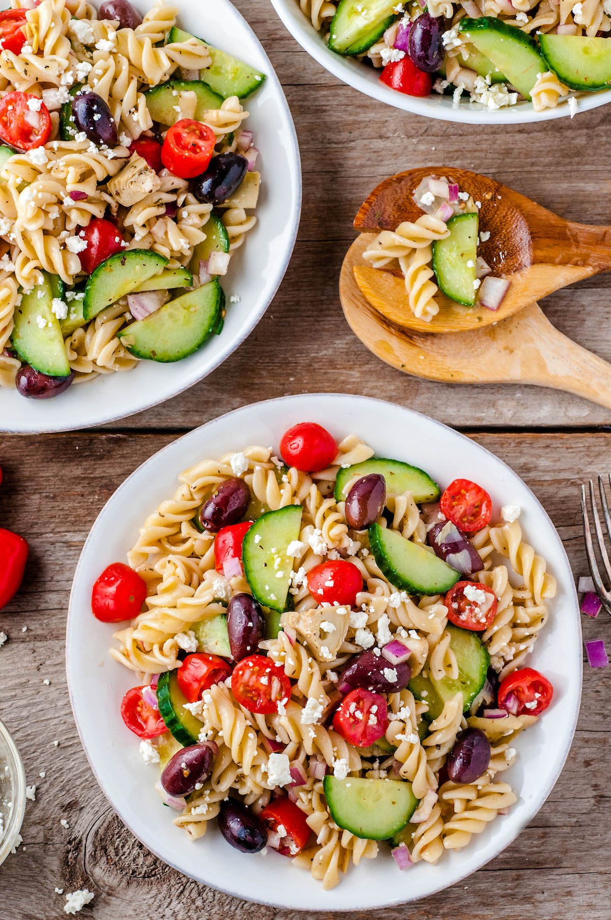 Overhead image of two bowls of pasta salad with two wooden spoons.