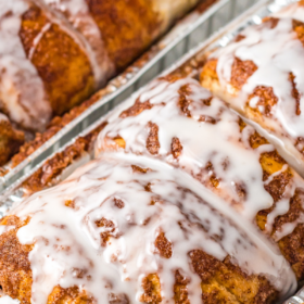 Cinnamon bread in metal tins with icing drizzled on top.