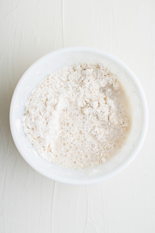 Dry ingredients in a white mixing bowl on a white work surface.