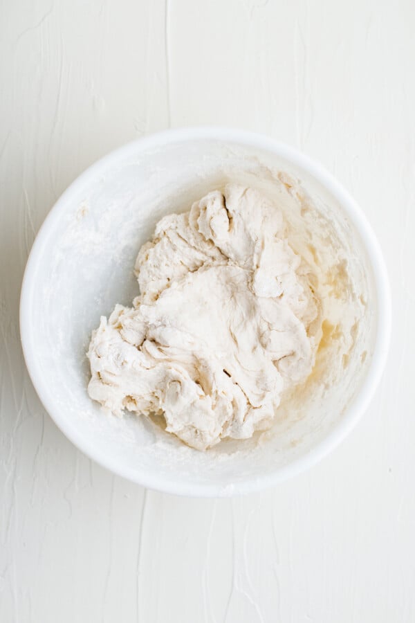 A white mixing bowl containing a soft, sticky white dough.