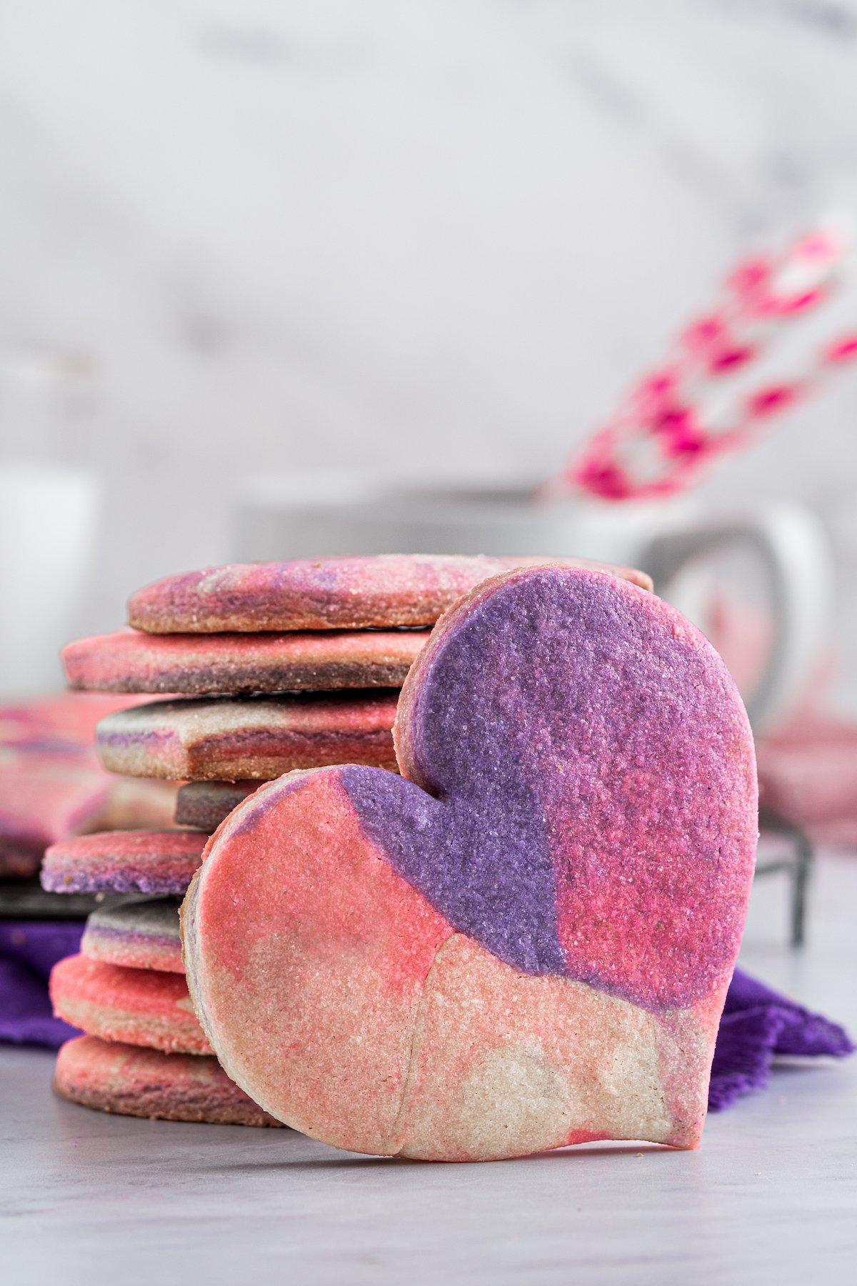 A stack of pink and purple cookies, with one cookie propped up against the stack.