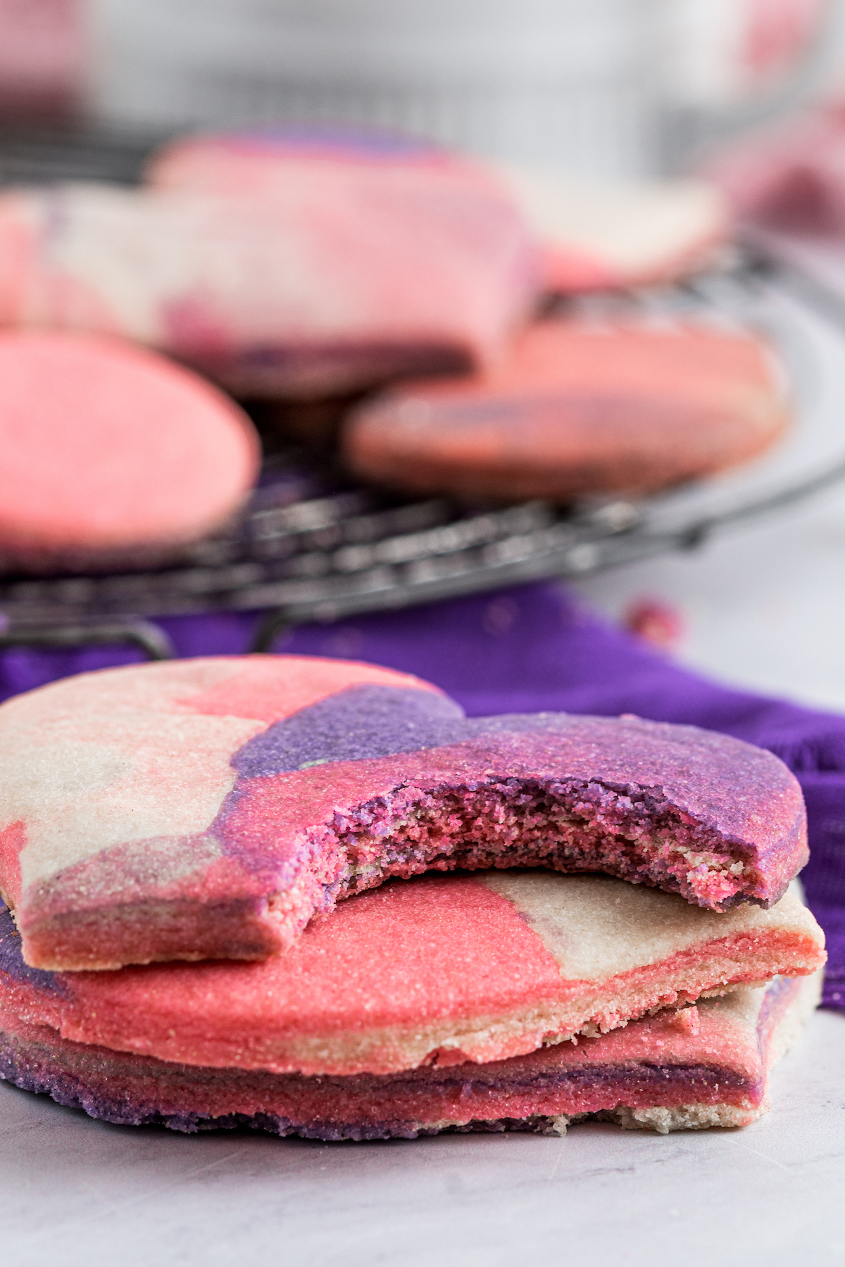 Several heart-shaped cookies in a stack. The top cookie has a bite taken out of it, to show texture.