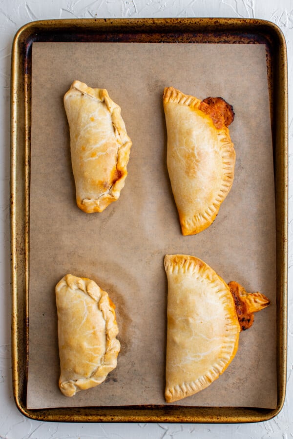 Baked empanadas on a parchment-lined tray.