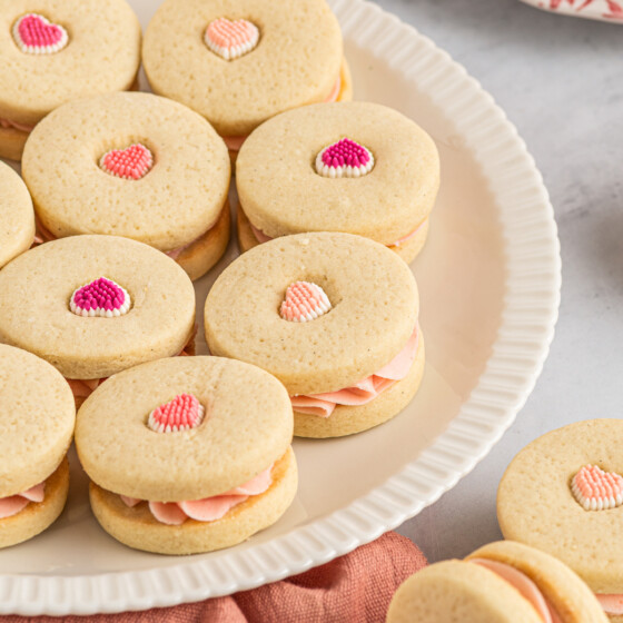 A platter with cookies on it. The cookies are decorated with candy hearts. Some of the hearts are dark pink, some are medium pink, and some are pale pink.