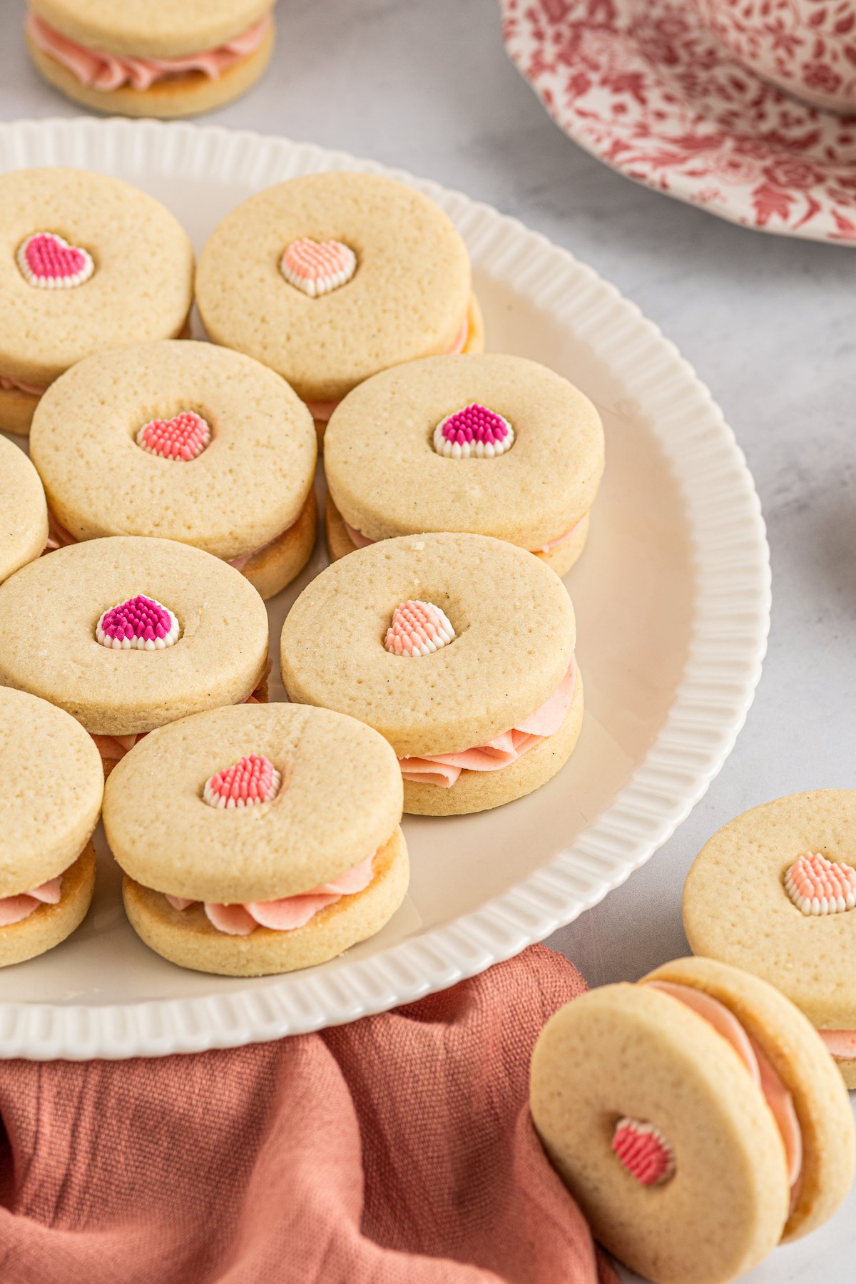 A platter with cookies on it. The cookies are decorated with candy hearts. Some of the hearts are dark pink, some are medium pink, and some are pale pink.