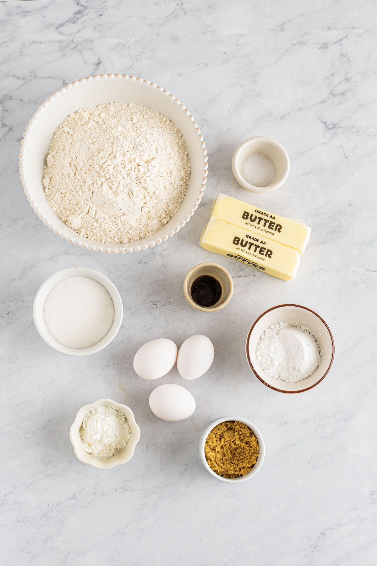 From top left: Flour, salt, granulated sugar, vanilla, butter, eggs, powdered sugar, cornstarch, brown sugar.