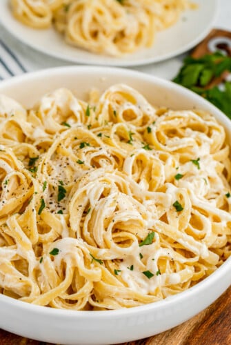 A white bowl of pasta in creamy sauce.