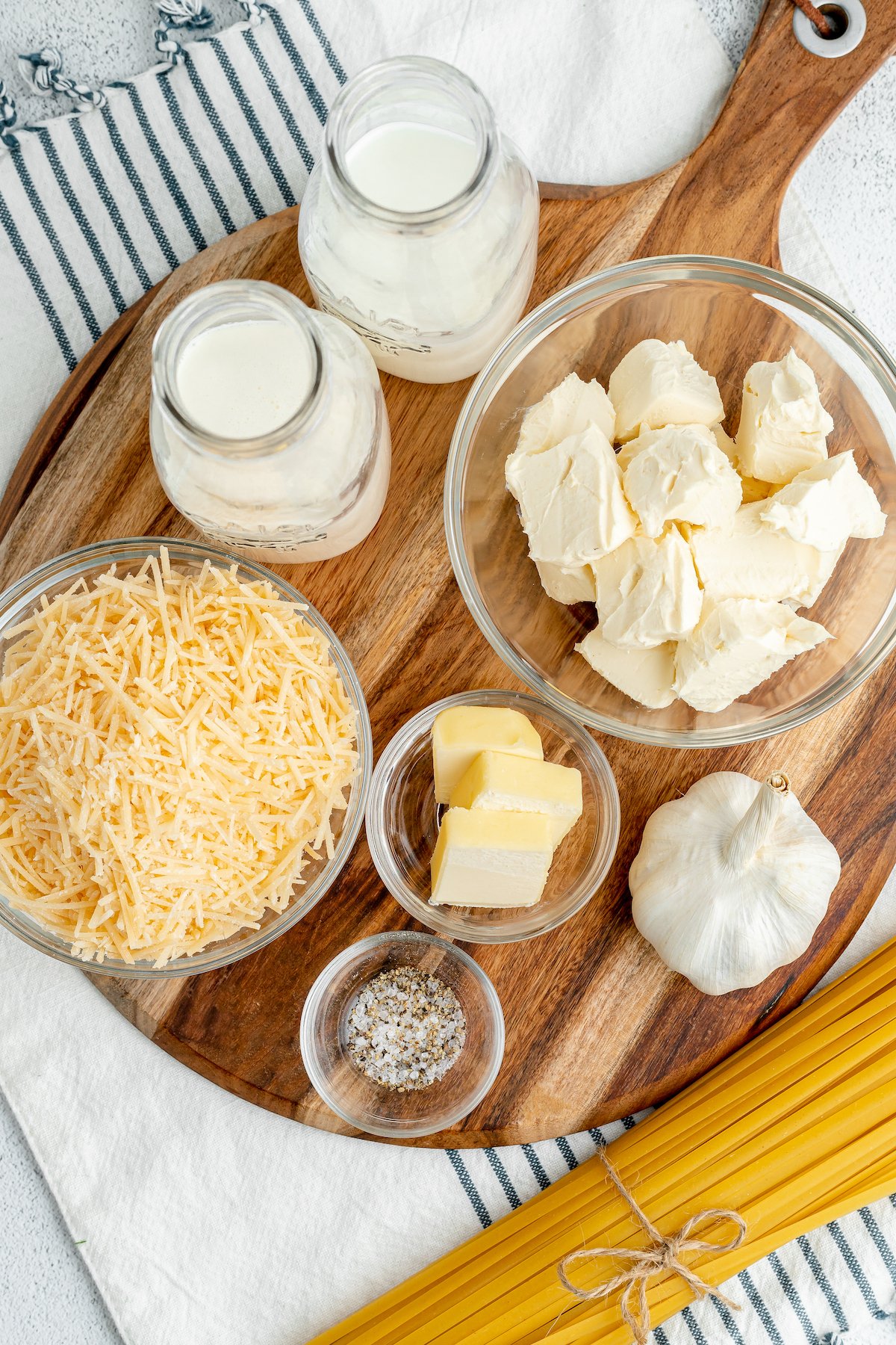 Clockwise form top: Milk, heavy cream, cubed cream cheese, garlic, butter, salt and pepper, shredded parmesan cheese.