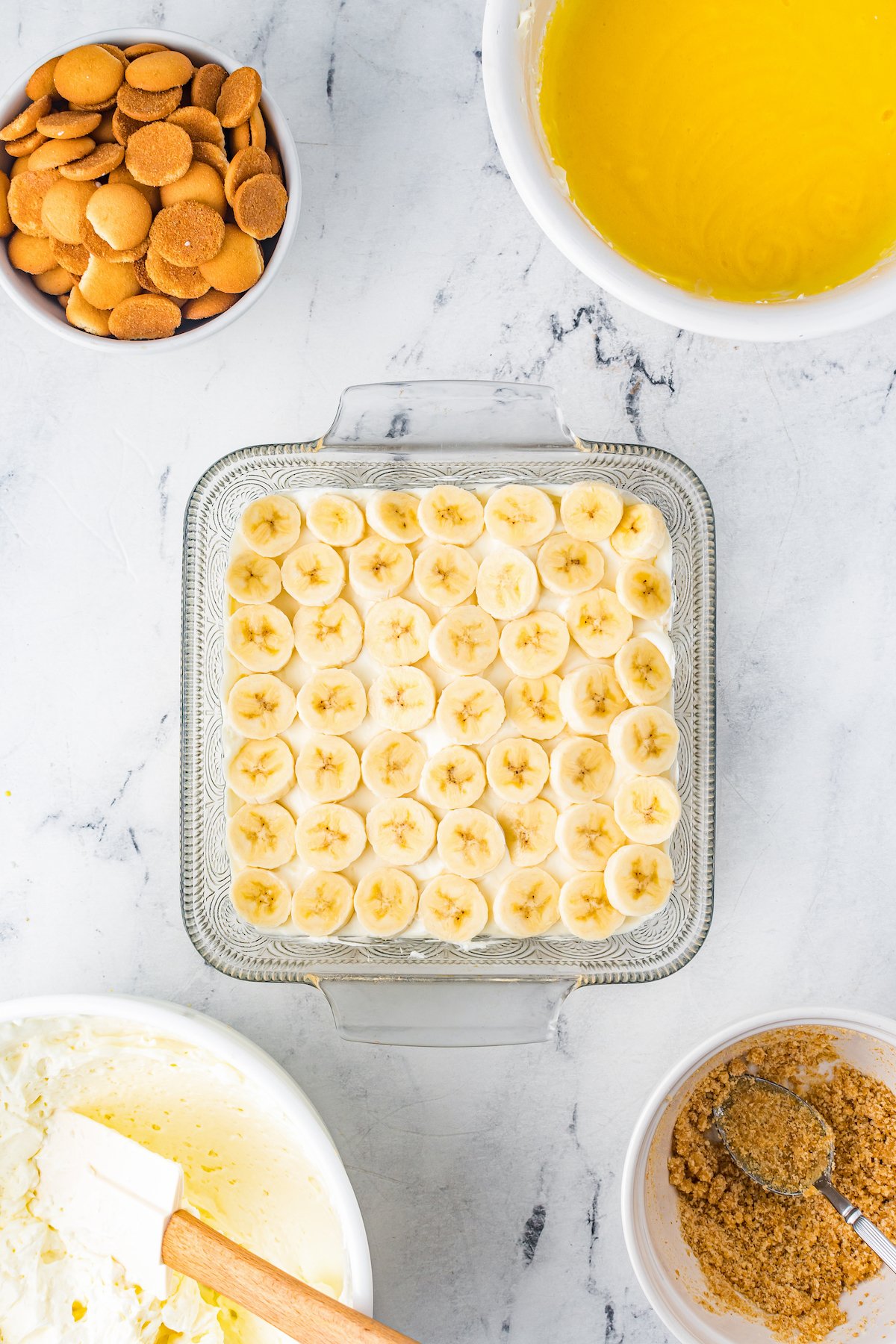 Overhead shot of a glass baking dish with a layer of bananas and cream cheese filling.