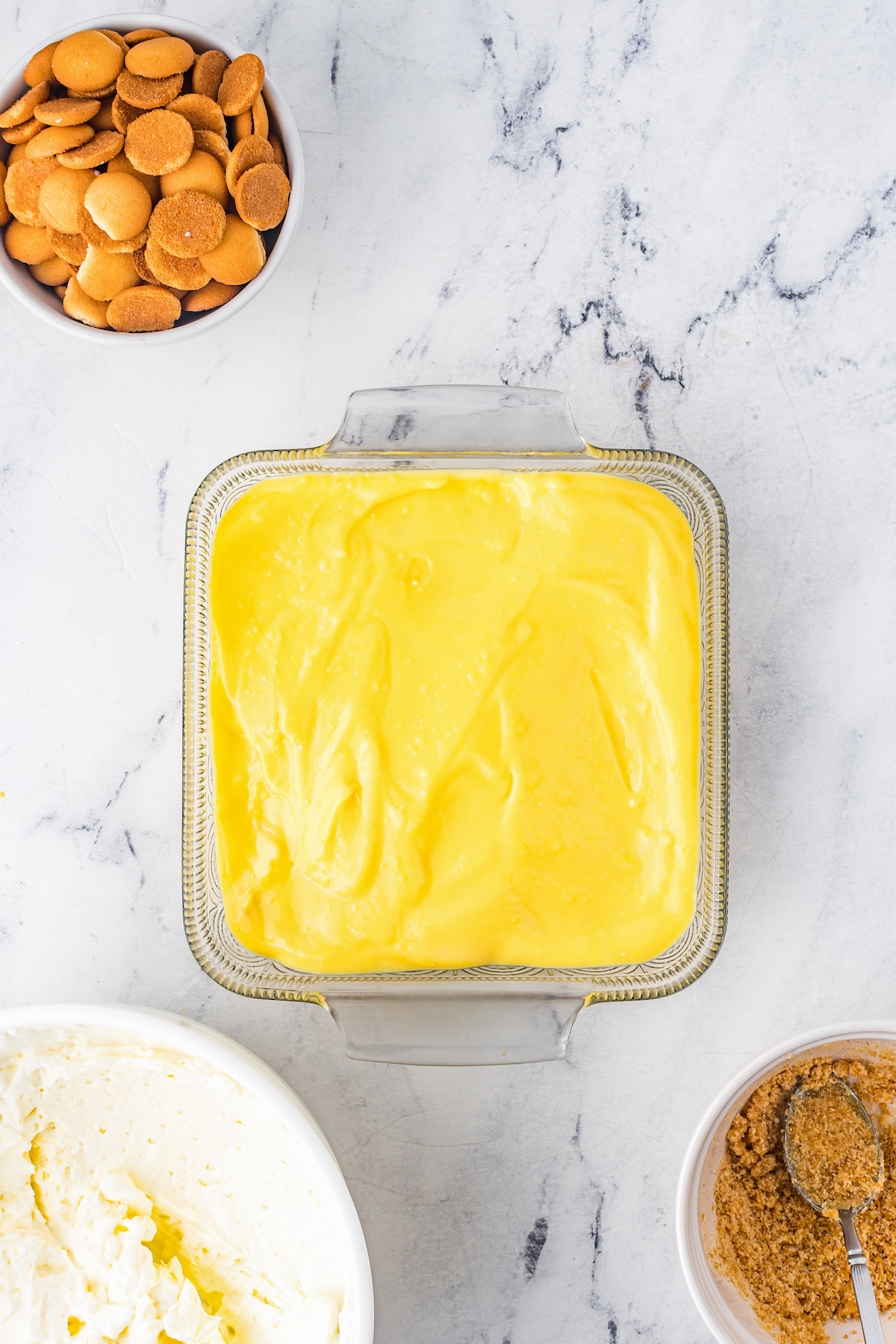 Overhead shot of a glass pie dish with a layer of vanilla pudding.