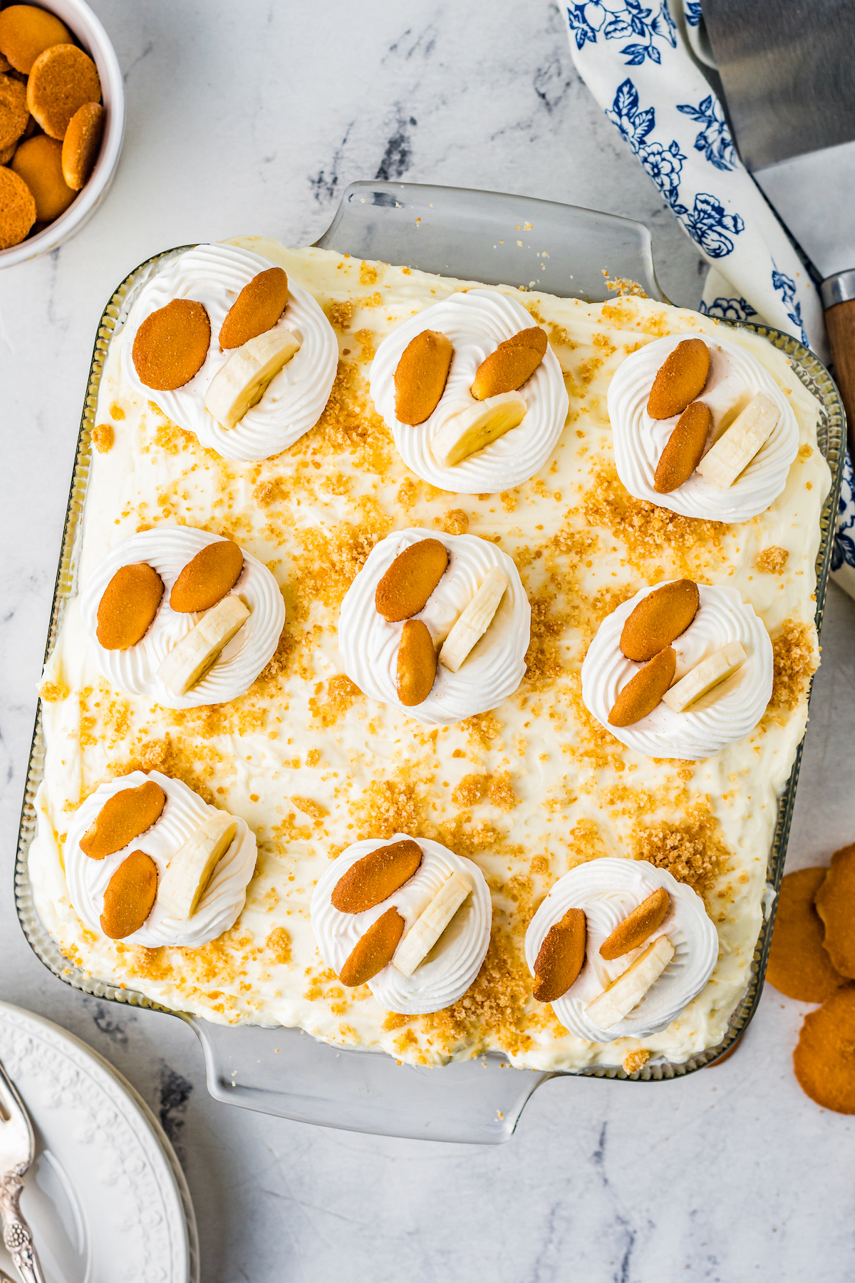 An overhead shot of a no-baked dessert topped with cookies, sliced bananas, and whipped cream.