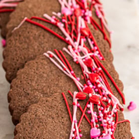 Chocolate sugar cookies on marble cutting board with valentine's sprinkles on top.