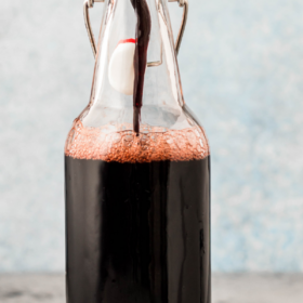 Elderberry syrup being poured into a bottle.
