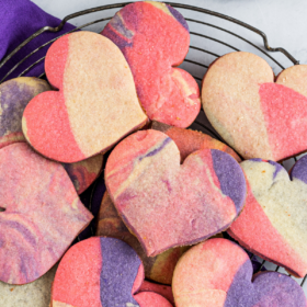 Overhead image of heart shaped marbled cookies on a cookie rack with a purple napkin.