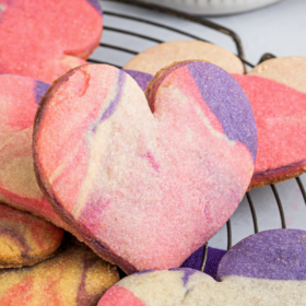 Up close image of heart shaped marbled cookies on a cookie rack with a purple napkin.