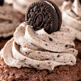 A chocolate cookie cup filled with Oreo cheesecake filling with a mini Oreo on top.