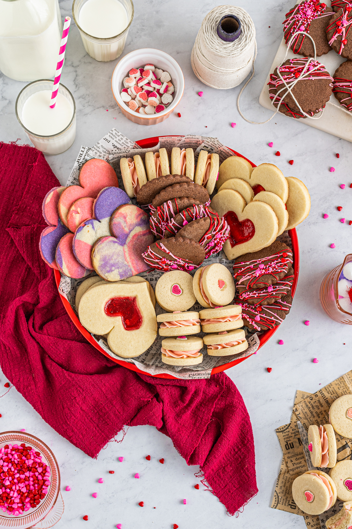 All kinds of Valentine's Day cookies on a cookie try with sprinkles and a red napkin.
