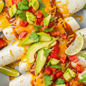 Chicken enchiladas in a smoky adobo sauce in a baking pan with fresh salsa on top.