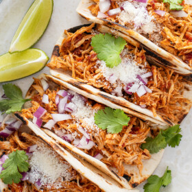 Shredded chicken tacos on a plate.