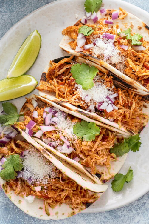 Shredded chicken tacos on a plate.