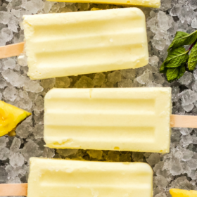 6 Dole whip popsicles on a bed of ice with fresh pineapple.