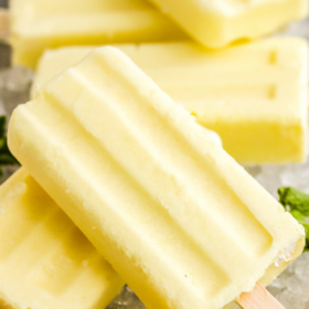 Dole whip popsicles on a bed of ice with fresh pineapple.
