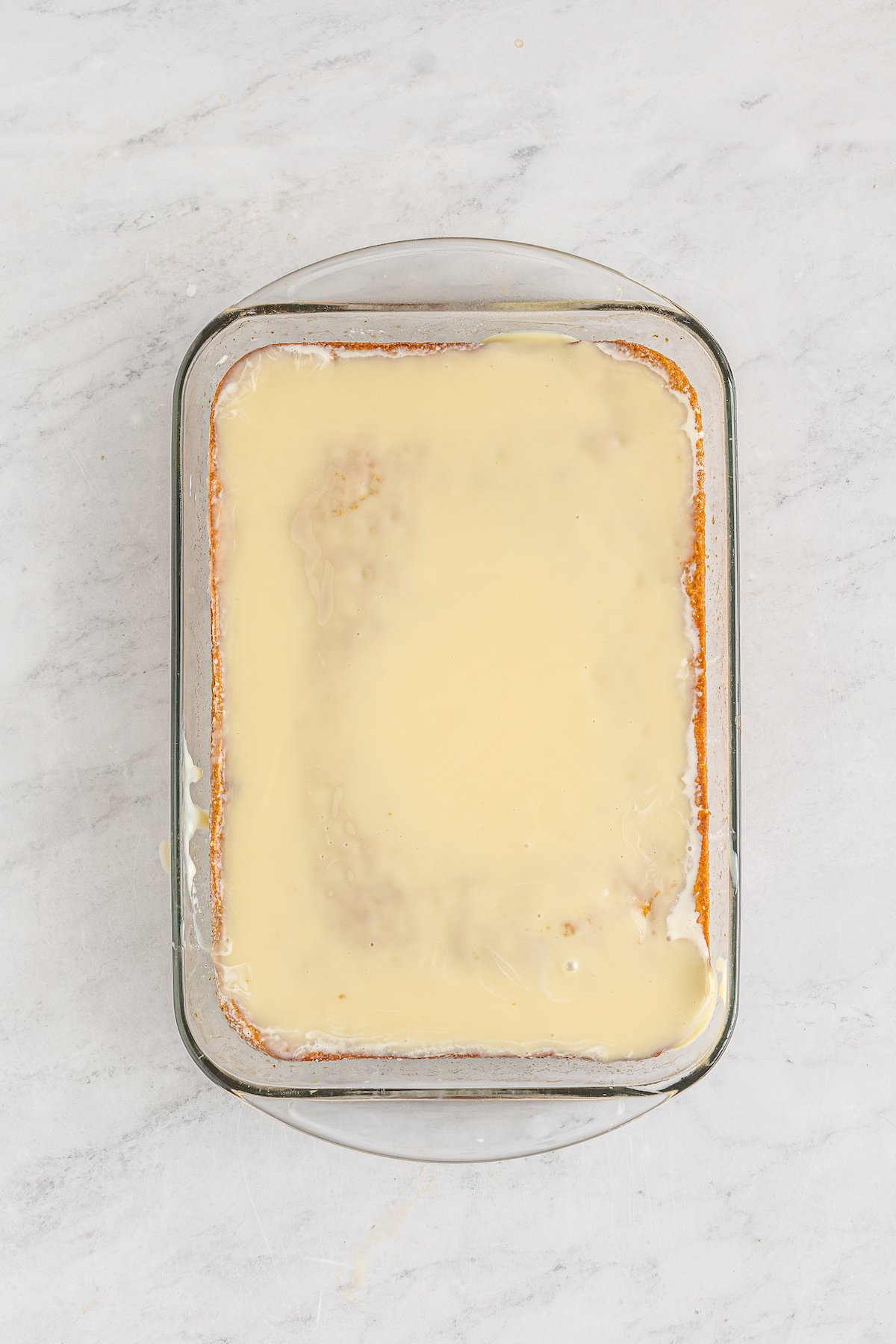 A sheet cake soaking in cream and milk.