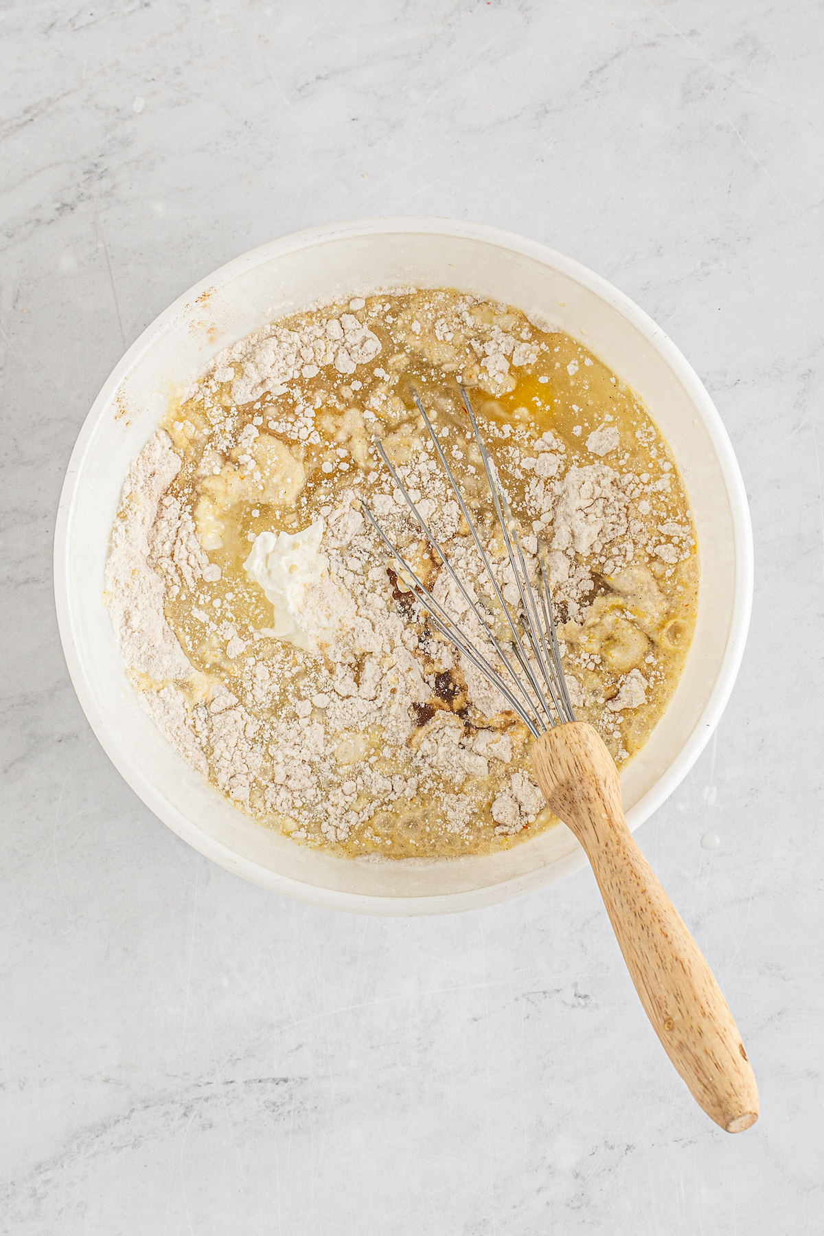 Dry and wet cake batter ingredients in a bowl with a whisk.