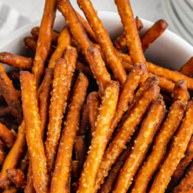 A bowl filled with honey mustard pretzels with salt and seasoning on them.