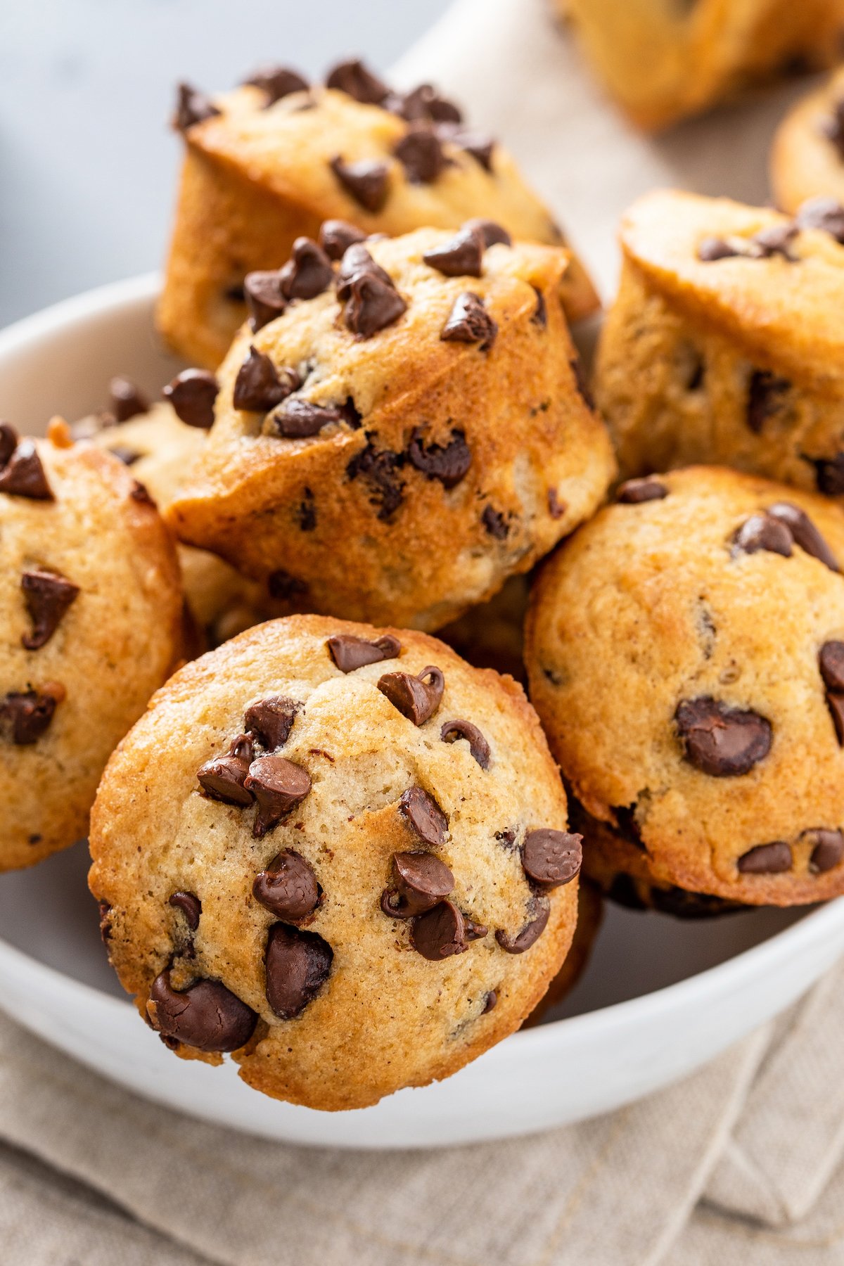 Mini muffins with chocolate chips, piled into a serving bowl.