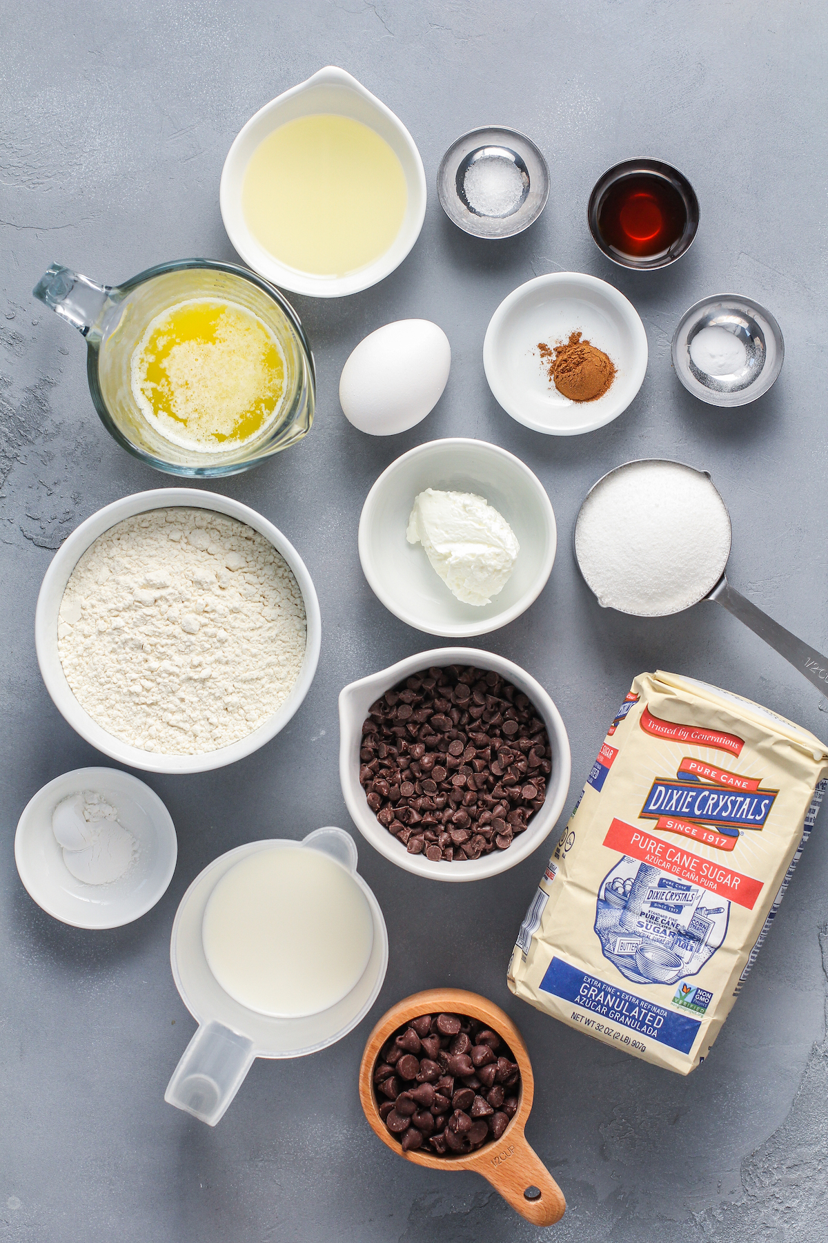 From top left: Oil, salt, vanilla, melted butter, egg, cinnamon, baking powder, flour, sour cream, sugar, baking powder, chocolate chip, milk, mini chocolate chips.