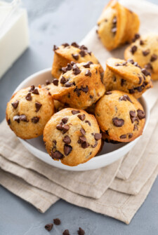 A bowl overflowing with mini chocolate chip muffins.