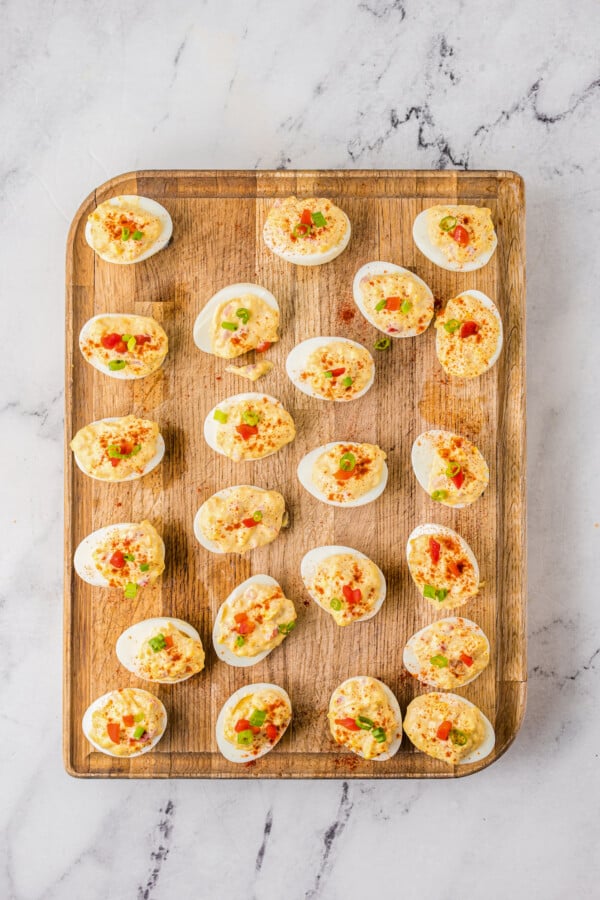 A wood cutting board with deviled eggs on top