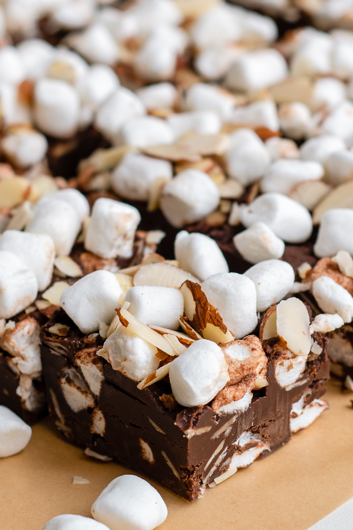 Close-up side view of rocky road fudge, showing the texture of the toppings and fudge.