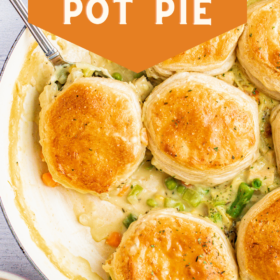 Skillet chicken pot pie with biscuits on top and a spoon scooping up a serving.
