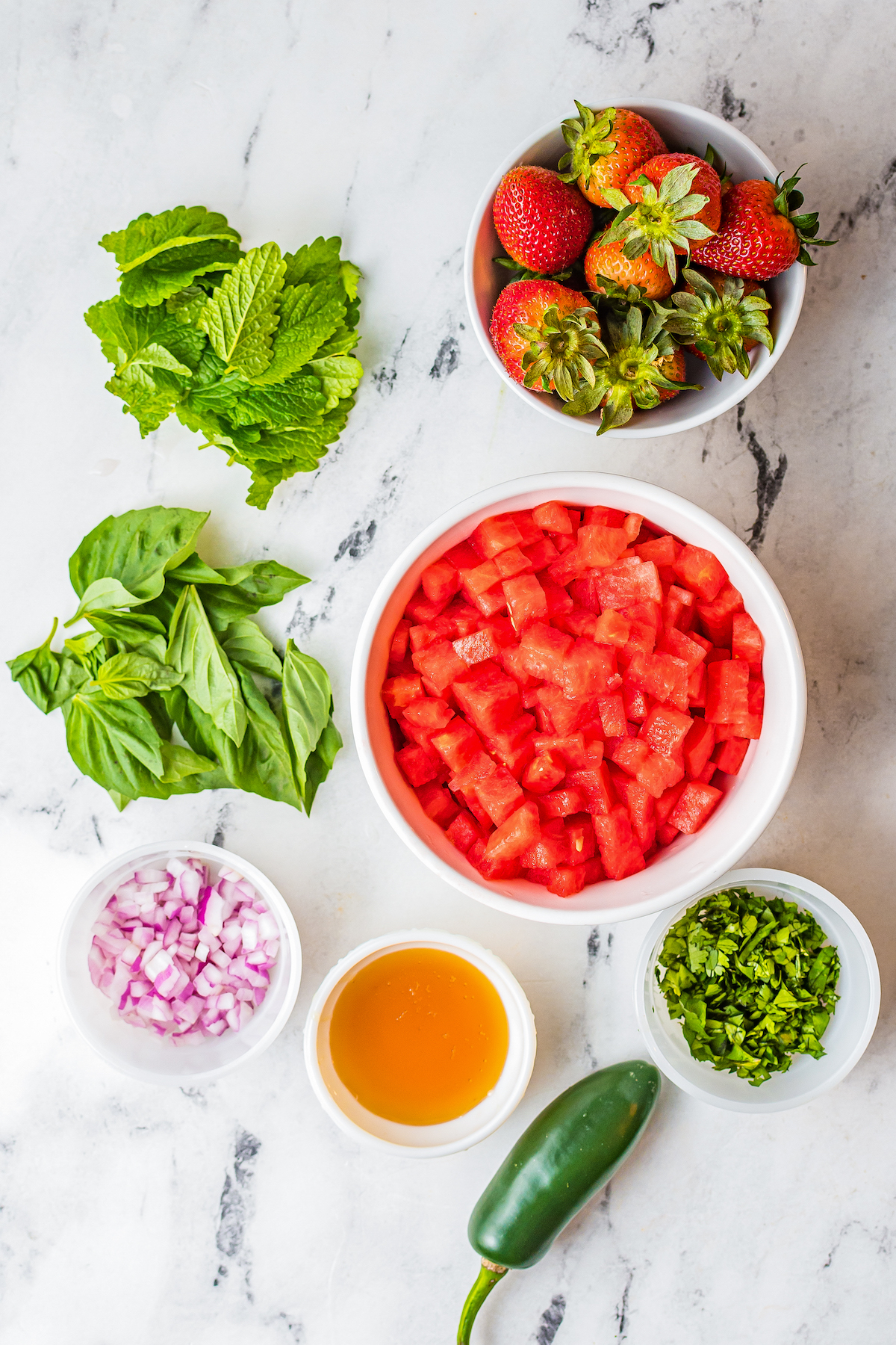 Clockwise from top: strawberries, chopped watermelon, finely chopped jalapeno, honey, onion, fresh herbs.