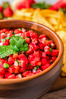 Salsa in a brown bowl, garnished with fresh mint.