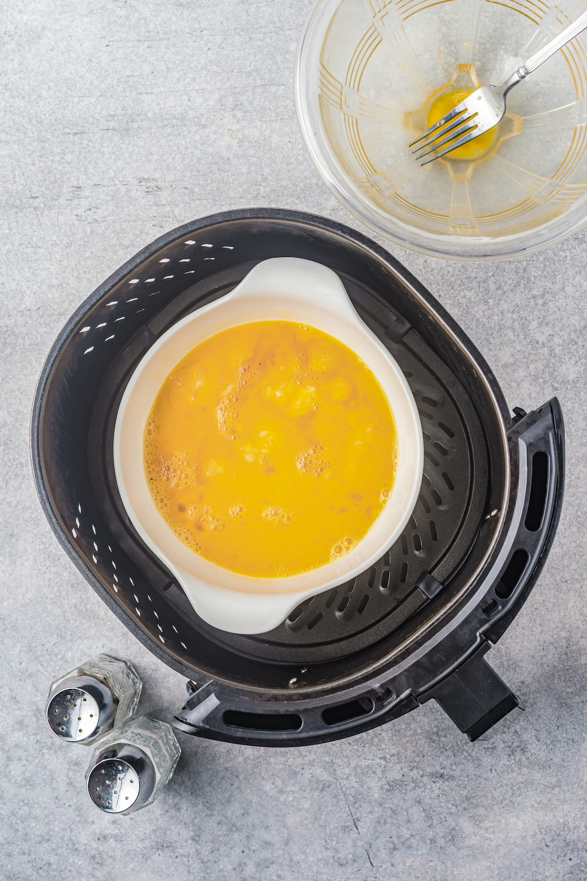 Partially scrambled eggs in a pot inside an air fryer.