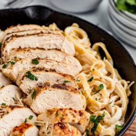 Chicken fettuccine alfredo, garnished with parsley, in a cast-iron skillet.