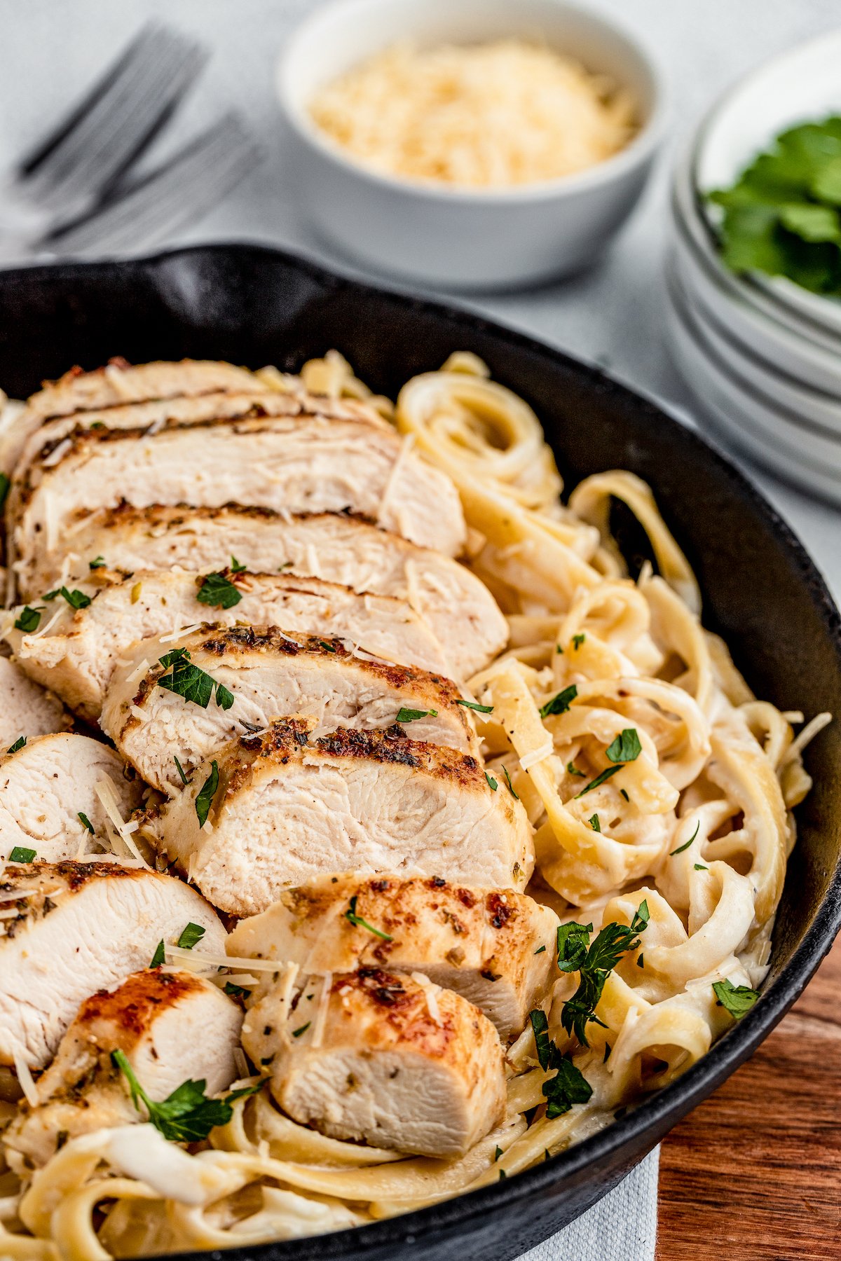 Chicken fettuccine alfredo, garnished with parsley, in a cast-iron skillet.