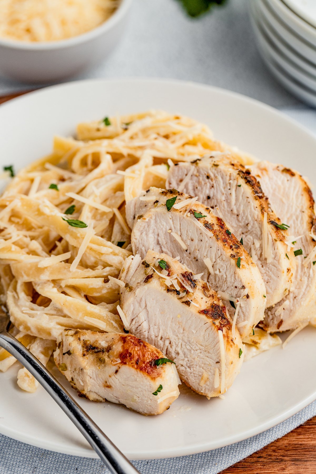 Fettuccine on a plate, with sliced chicken fanned along the side of the pasta.